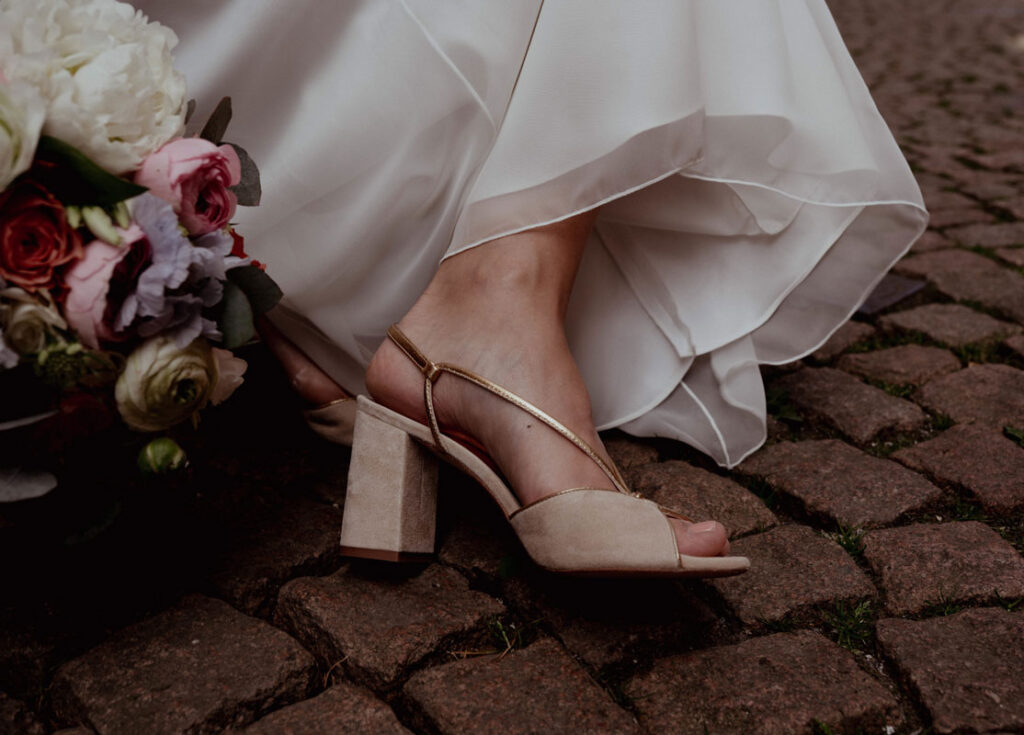 Detailaufnahme eines Brautschuhs neben einem Blumenstrauß im Rahmen der Dokumentation durch Alina Lowe