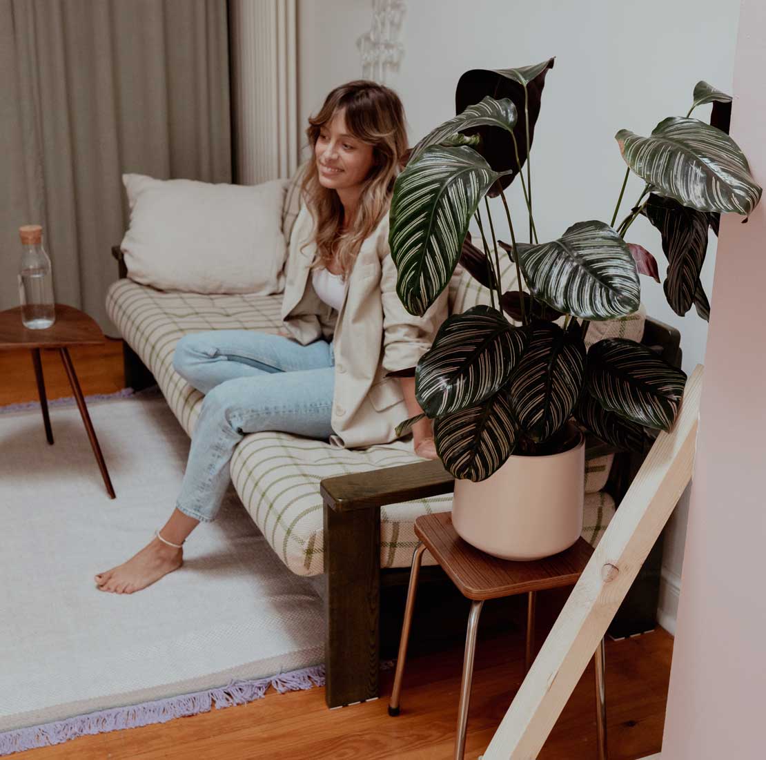 Alina Lowe sitzt auf dem Sofa in ihrem Atelier La Fleur. Im Vordergrund sind Pfanzen und Ihre Fotowand zu erkennen. Sie ist in einem Gespräch und erzählt über Ihre angebotenen Leistungen im Bereich der Hochzeitsfotografie, Porträtfotografie und Familenfotografie.